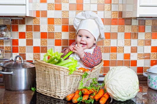 Child sits in a wattled basket on a table with vegetables