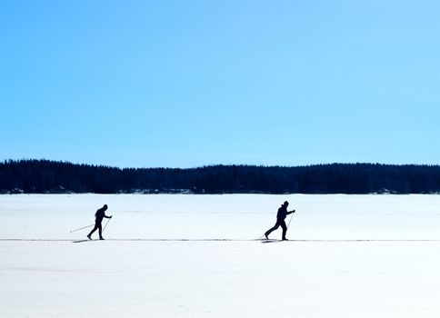 Skiers nordic skiing on frozen lake winter trail
