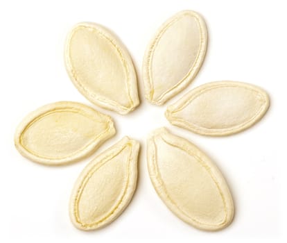 Pumpkin seeds arranged in flower shape on white background.