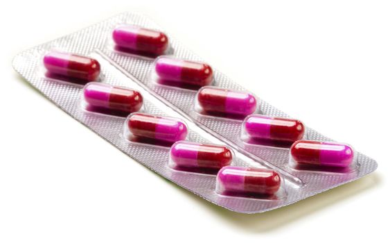Pack of medical red and pink capsules on white.