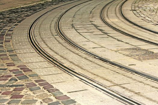 Bending tram rails on the road covered with cobblestones