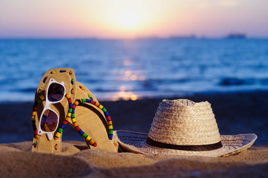 Wicker hat, sandaland glasses on the sandy beach