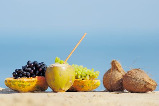Papaya, coconut, nut and grapes on the sand