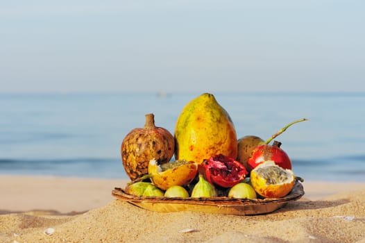 Exotic tropical fruit on the leaves plate, on the sandy beach