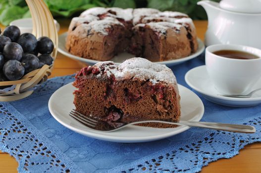 a piece of sponge cake with plum and a cup of tea