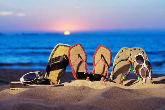 Beach sandals and glasses on the beach in evening