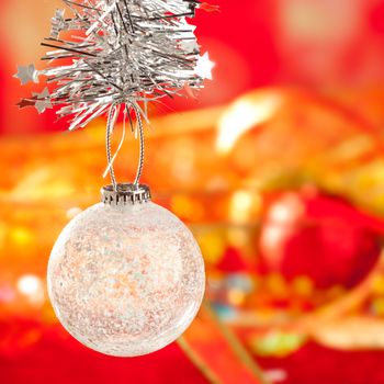 Christmas card tinsel snow crystal bauble on red blurred background