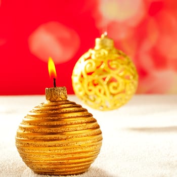 Christmas golden candle and bauble on snow an red background