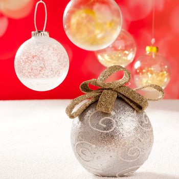 Christmas silver bauble with golden loop on snow red background