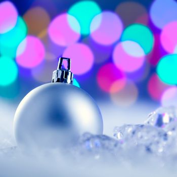Christmas silver bauble in colorful blurred lights background