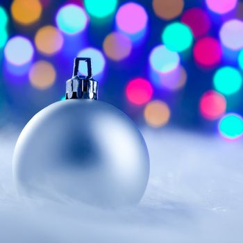 Christmas silver bauble in colorful blurred lights background