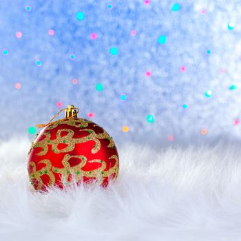 christmas bauble on white fur and colorful lights