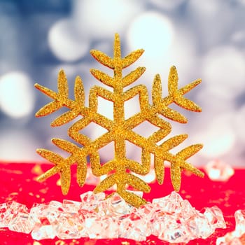 Christmas golden snowflake on ice cubes with blue lights bokeh background