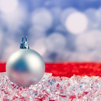 Christmas silver bauble on ice cubes with blue lights bokeh background