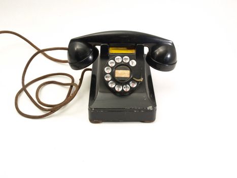 An antique black rotary dial telephone isolated against a white background.