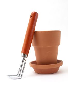 Gardening tool and terra cotta pot and saucer isolated against a white background.