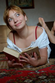 Girl lying on the carpet and reading a book