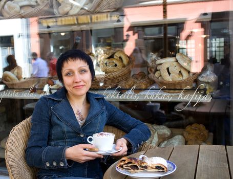 Young woman enjoying cappuccino and strudel at a cafe