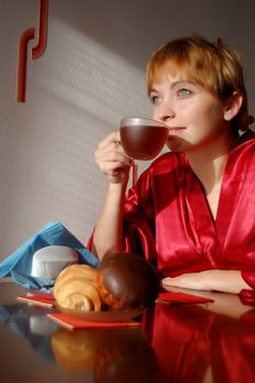 girl having breakfast with cup of tea and croissant