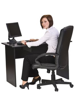 Young businesswoman at her desk working on the computer and looking back over the shoulder.