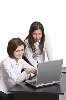 Two young businesswoman working together on a laptop at their office desk.