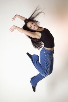 Smiling Asian woman leaping with hair flying