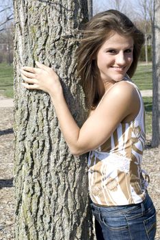 A beautiful and cute model outside stading next to a tree.