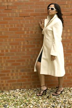 A beautiful model outside against a brick wall.