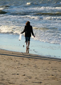 The barefooted girl collects amber on seacoast