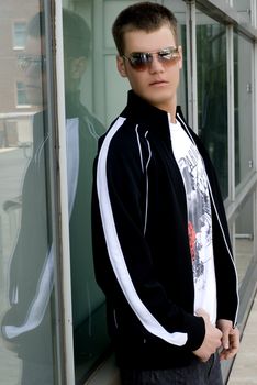 A young man outside against a wall.