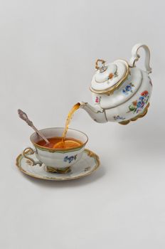Tea pours into a cup with lemon from teapot