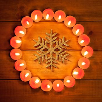 christmas candles circle over wood and golden snowflake symbol