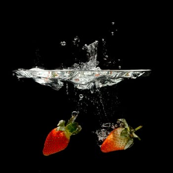 strawberry splashing in water over black background