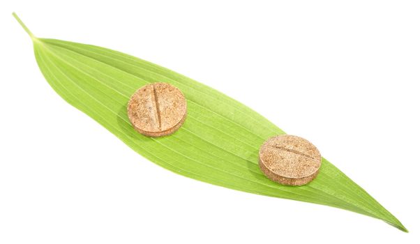 Curative pills on a green leaf.