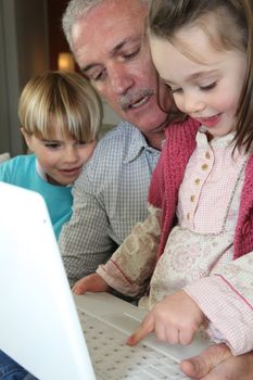 grandfather and grandchildren with laptop