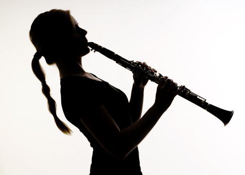 Female Musician Practices her Woodwind Technique on a Clarinet Photographed in silhouette