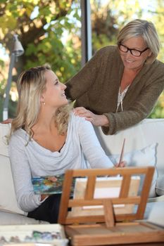 Woman encouraging a young painter at home