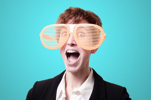 businesswoman with big funny eyeglasses screaming on blue background