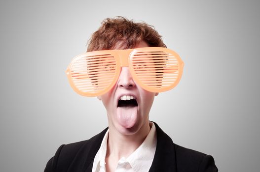 businesswoman with big funny eyeglasses and tongue out on gray background