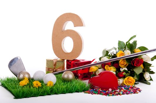 Roses, a golf club and golf balls on an artificial peace of grass to be used as a birthday card