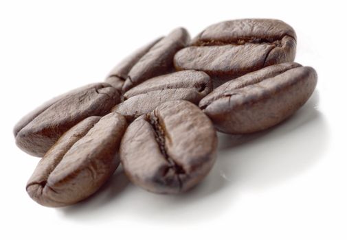 Seven coffee beans on the white background. Flower made of coffee beans. Soft focus.