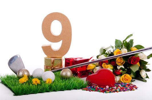 Roses, a golf club and golf balls on an artificial peace of grass to be used as a birthday card