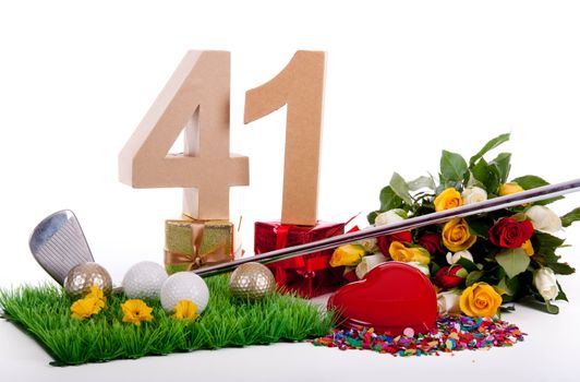 Roses, a golf club and golf balls on an artificial peace of grass to be used as a birthday card