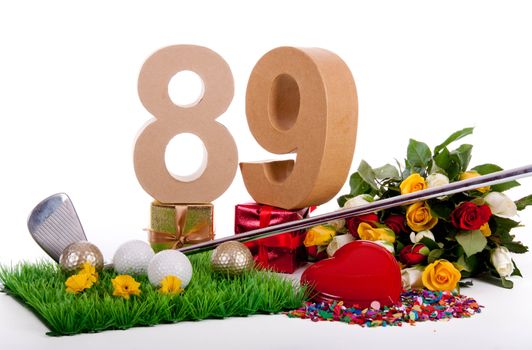 Roses, a golf club and golf balls on an artificial peace of grass to be used as a birthday card