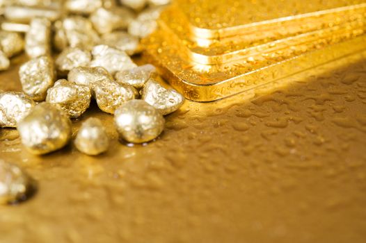 fine gold ingots and nuggets on a wet golden background