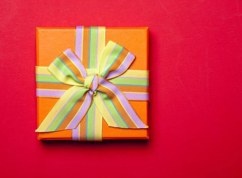 Orange Gift Box With Bow On Red Background