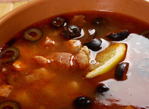 Solyanka on the plate.Solyanka, Russian soup with beef,sausage,chicken and lemon, olives