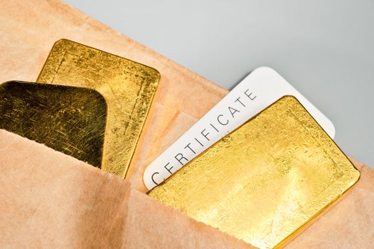 Processing and global trading of precious metals. Gold bars, certificate and paper pack. Closeup.