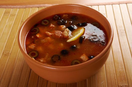 Solyanka on the plate.Solyanka, Russian soup with beef,sausage,chicken and lemon, olives