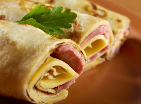 rolled pancakes stuffed ham and cheese. Shallow depth-of-field.